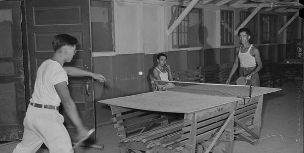 two boys are playing ping pong/table tennis in the early 1900's